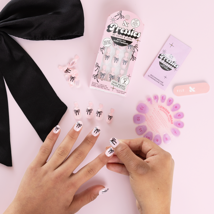 Biggest Bow On Top - Pressies | Short Medium | Round showing pale pink press-on nails with black bow design and application tools by Olive and June