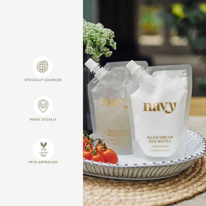 Navy hand cream eco refill packaging on a woven mat with tomatoes and a plant.