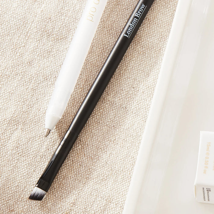 Eyebrow pencil and products on a beige surface with 'London Brow' branding.