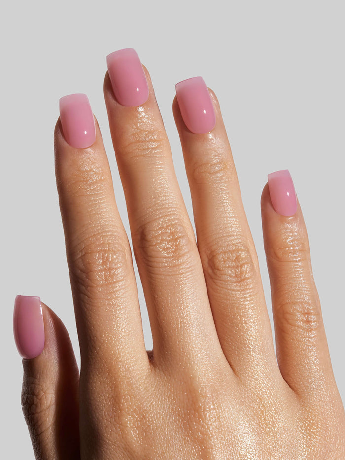 Hand with pink press-on nails on a plain background