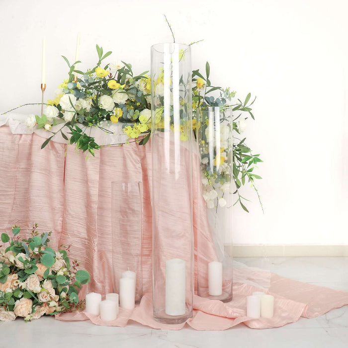 Elegant glass candle holders with floral arrangements on a pink tablecloth.