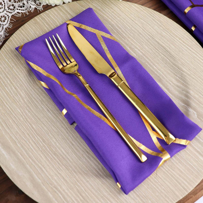Purple napkin with gold cutlery on a round table setting.