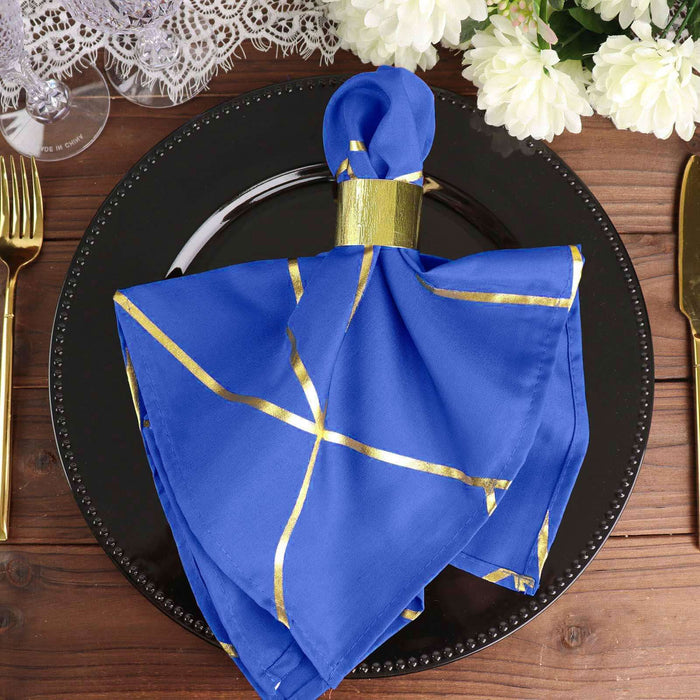 Blue cloth napkin with gold accents on a black plate, styled for a dining setting.