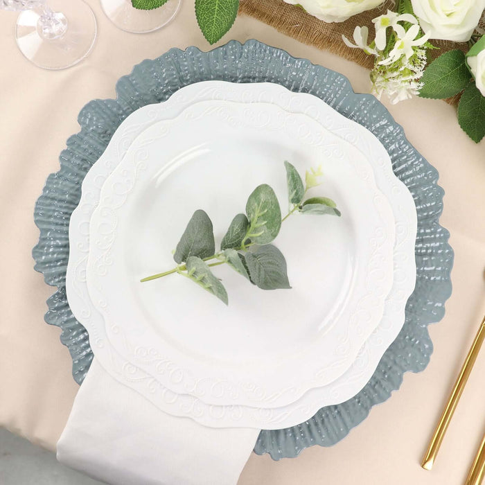 Elegant white plate on blue scalloped charger with greenery accent