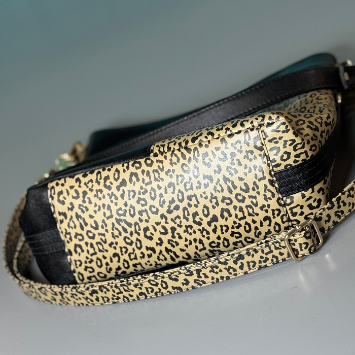 This shoulder bag is made with a textured black vinyl and a leopard print vinyl. It also has a matching crossbody strap. This photo shows the bottom of the bag.