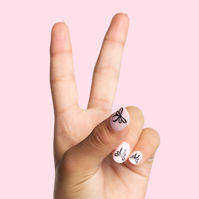 Biggest Bow On Top - Pressies | Short Medium | Round showing light pink press-on nails with black bow design on pale pink background