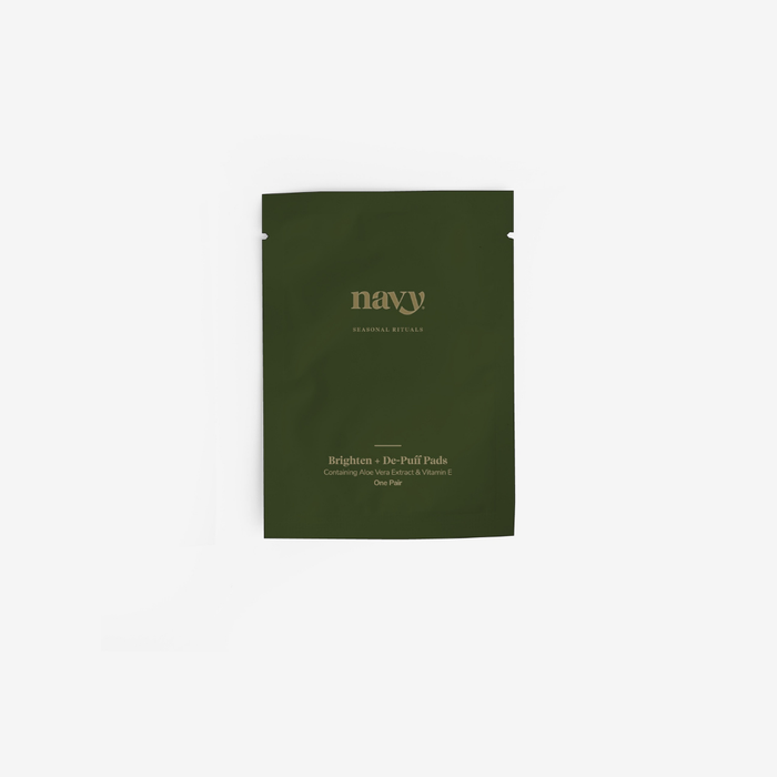 A dark green stand-up pouch of navy Cosmetics Brighten + De-Puff Pads on a clean white background.