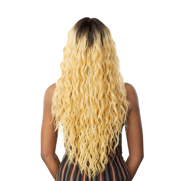 Back view of SENSATIONNEL Butta Lace Unit 11 wig long wavy blonde hair with dark roots on model