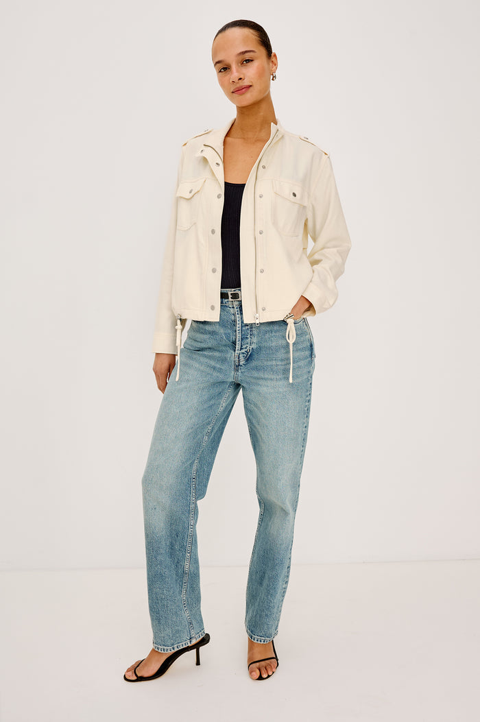 Collins Miitary Inspired Jacket With Shoulder Epaluettes, Stand Collar, Front Snap Buttons, Double Chest Pockets, Long Sleeves in Ivory Colorway - Full Body Front View Featuered on Model