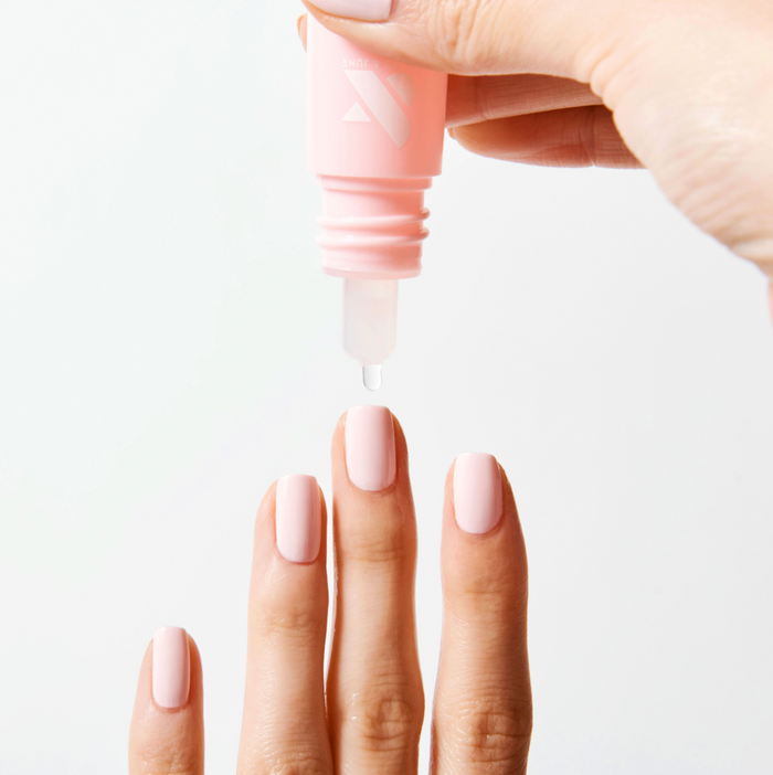 Drop from Dry Drops bottle about freshly manicured nails with soft pink polish for quick drying polish care