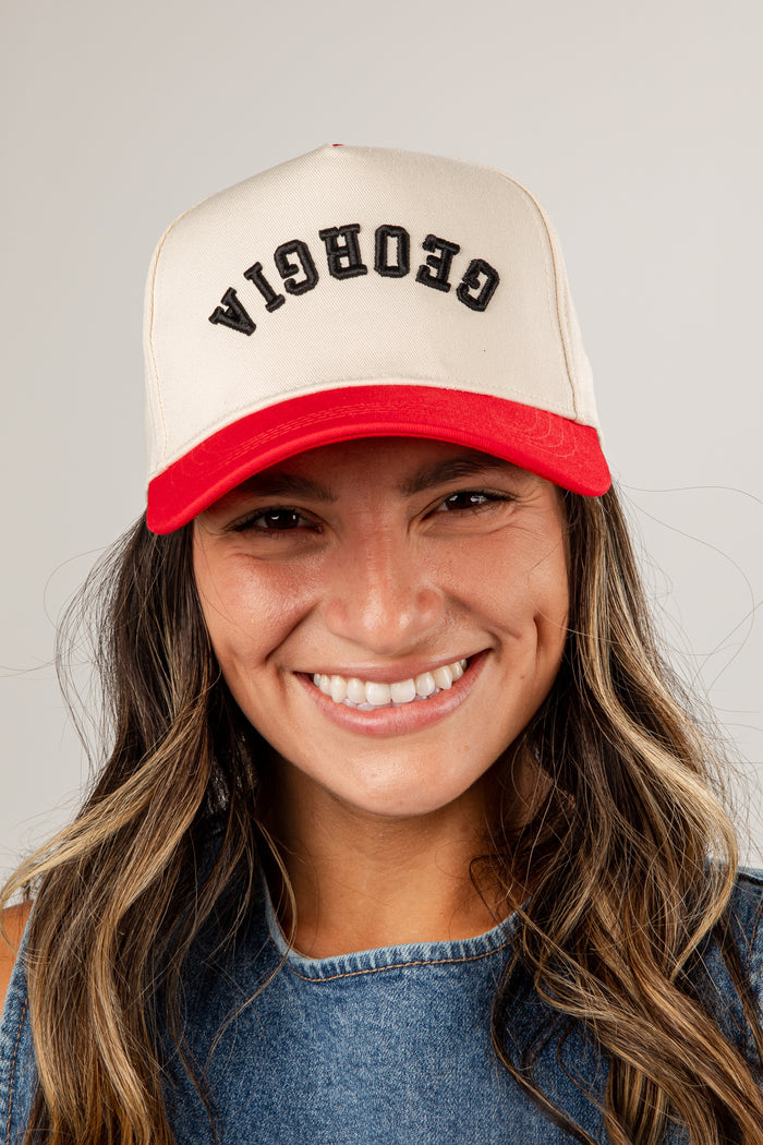 Person wearing a beige and red cap with 'Georgia' text on a plain background