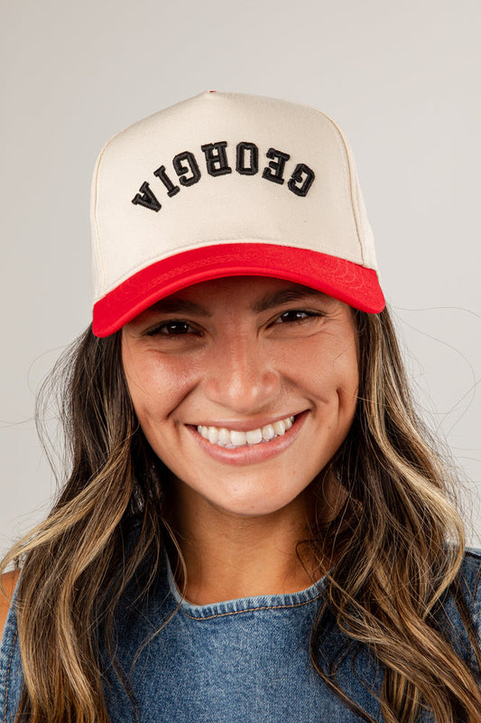 Person wearing a beige and red cap with 'Georgia' text on a plain background