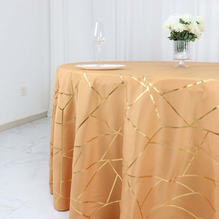 Elegant gold-patterned tablecloth on a round table with a glass and flowers.