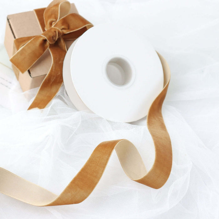 Brown ribbon spool with a gift box and delicate fabric backdrop.