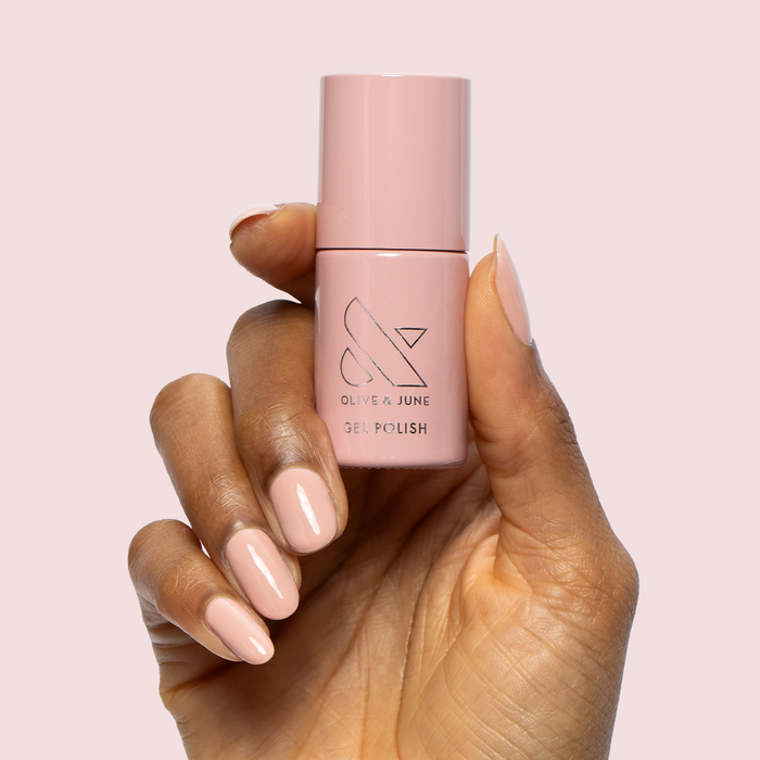 HZ - Gel bottle held by hand with matching soft rosy neutral gel polish manicure on almond-shaped nails