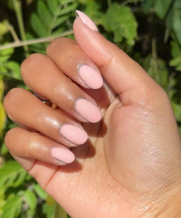 HZ - Gel soft rosy neutral gel polish manicure on almond-shaped nails with natural outdoor lighting and greenery background