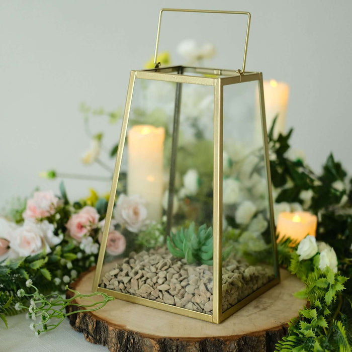 Decorative glass lantern with succulent and stones, surrounded by flowers and candles.