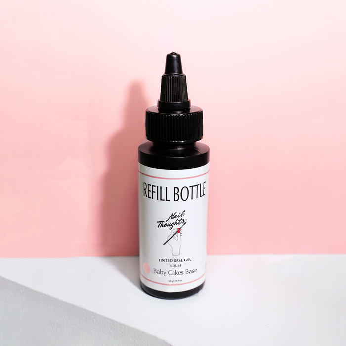 A bottle of NTB-R24 BABY CAKES BASE 50G nail polish in a sheer peach color, positioned against a pink background.