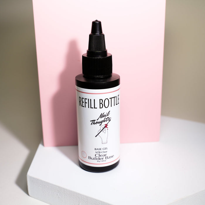 A bottle of Nail Thoughts clear base gel refill, placed on a white surface with a pink background.