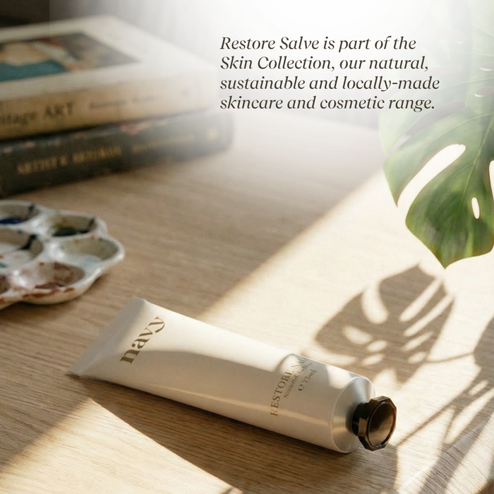 Tube of 'Restore' salve on a wooden surface with books and a plant in the background.