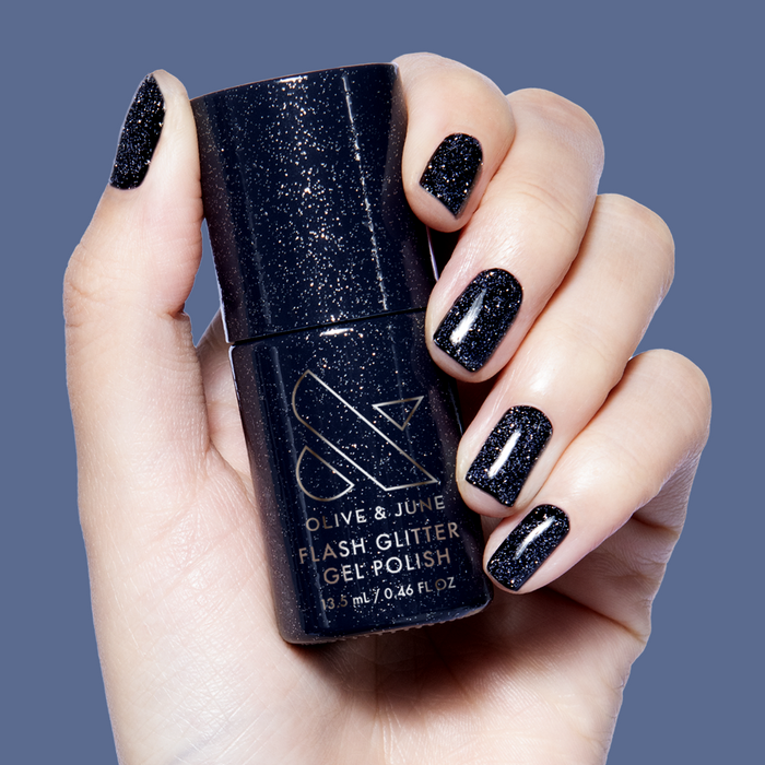 Hand displaying black glitter nails holding Out Past Curfew Gel bottle with sparkling gel polish for long-lasting mani