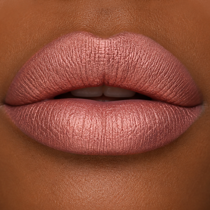 close-up lip image of darker skin model wearing Runway Rogue SilkGlam Long Wear Liquid Lipstick in Paparazzi, a frosted peachy nude shade