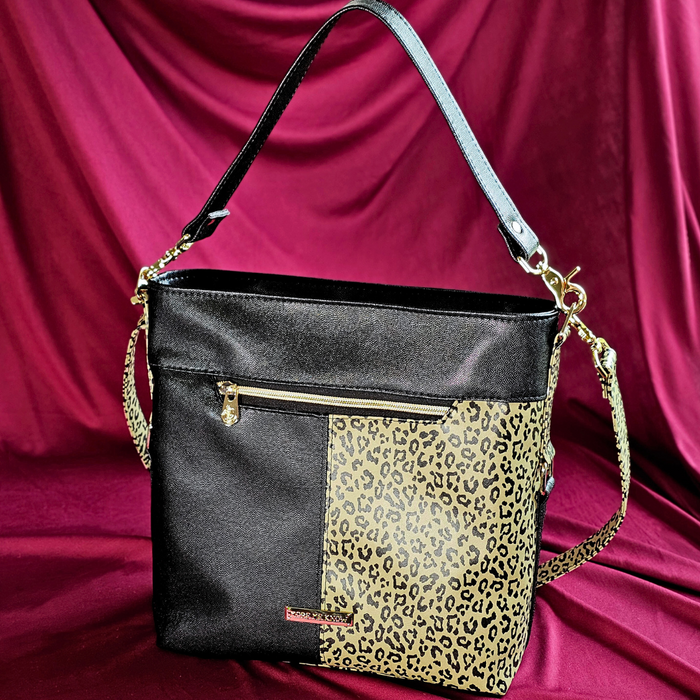This shoulder bag is made with a textured black vinyl and a leopard print vinyl. It also has a matching crossbody strap.