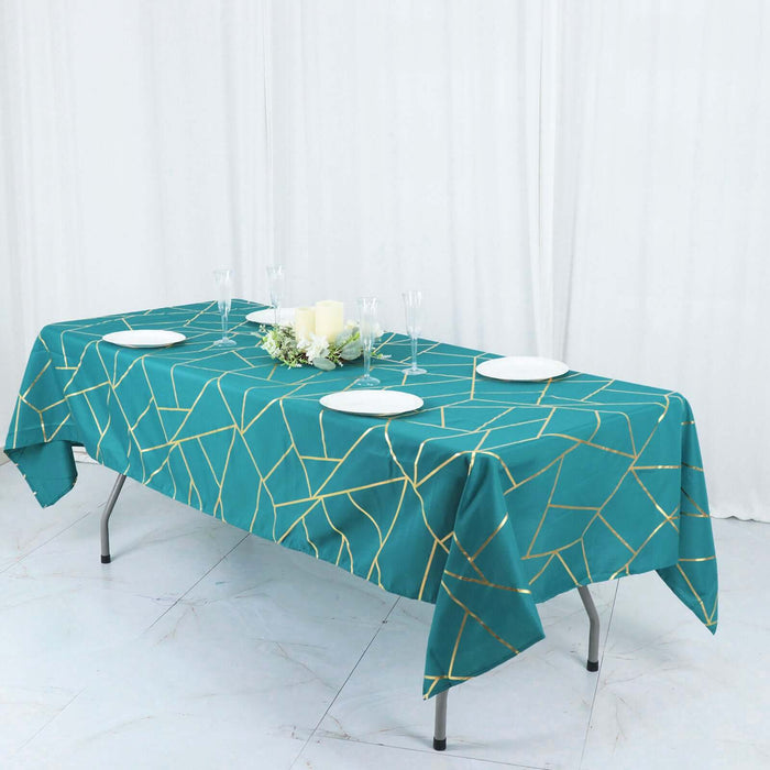Teal geometric tablecloth draped over a table with plates and decor.
