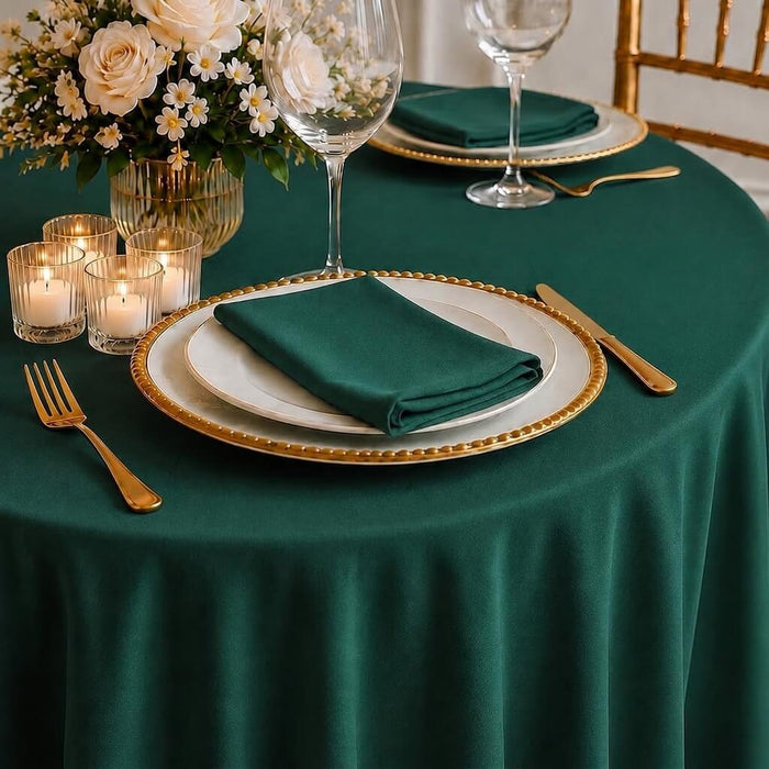 Hunter emerald green round tablecloth on a dining table with floral centerpiece.