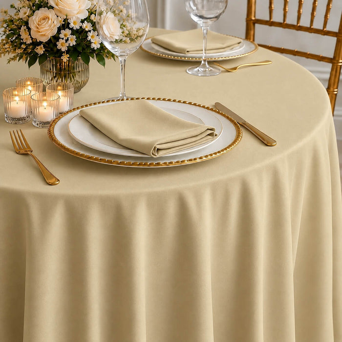 Champagne round tablecloth on a dining table with elegant settings.