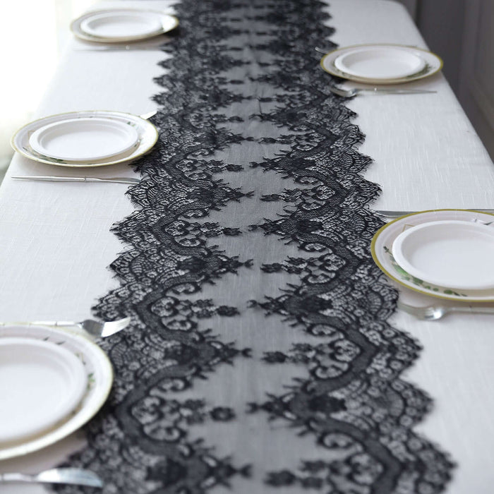 Elegant black lace table runner on a white table setting with plates and cutlery.