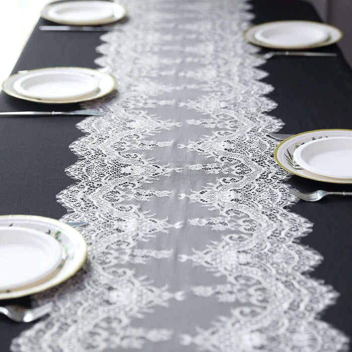Lace table runner on a black table with white plates arranged neatly.