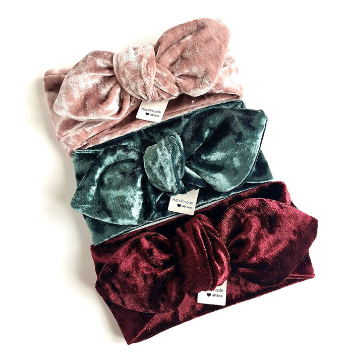 Set of three velvet bow turbans in blush pink, emerald green, and deep wine, featuring a knotted bow detail. Handmade for babies and toddlers, perfect for holidays, special occasions, or stylish everyday wear.