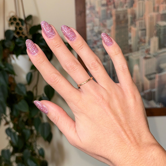 Hand with nails polished in Rosé Rhymes with Partay Gel showing cool-toned pink flash glitter manicure