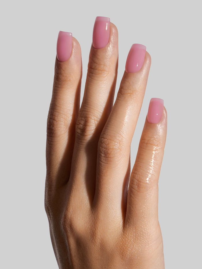 Hand with pink press-on nails on a plain background