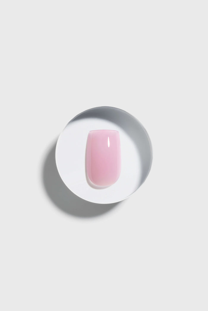 pink press-on nail on a white plate with a gray background