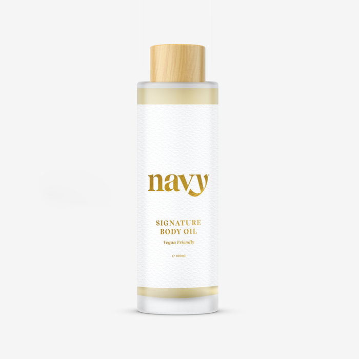 Navy Signature Body Oil,  with white labels and gold text, containing natural seed oils for hydration.