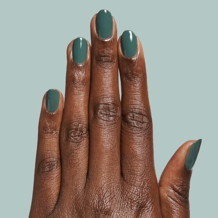 Hand with oval nails painted in Still Life of Flowers - Gel mossy green gel polish against soft muted background