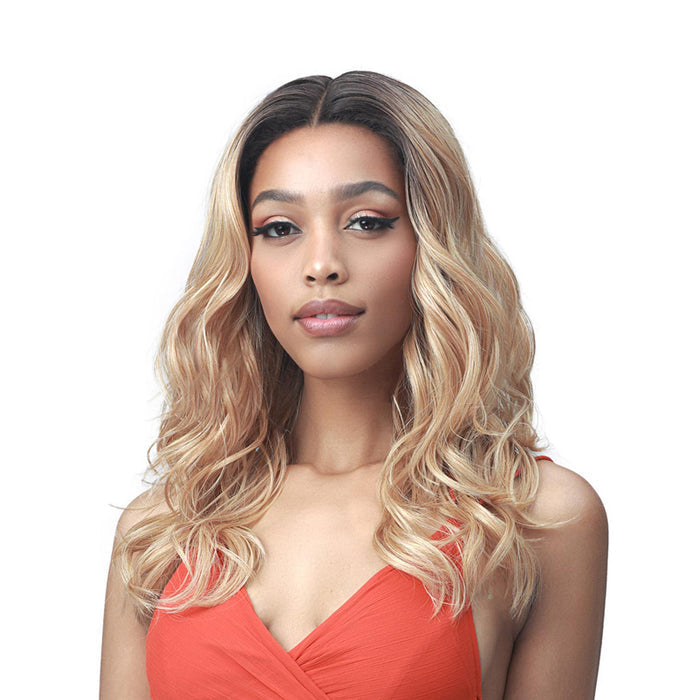 Model wearing Bobbi Boss Addison lace front wig in honey blonde with dark roots center part and soft waves