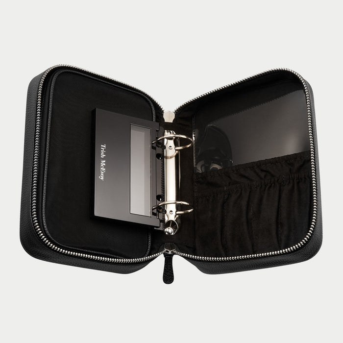 Black zippered case with a ring binder inside on a light gray background