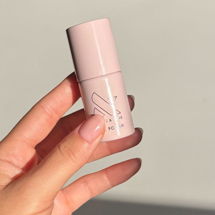 The Queen Takes Her Tea With Milk - Gel bottle held by hand with sheer neutral mauve nails for a natural mani by Olive and June