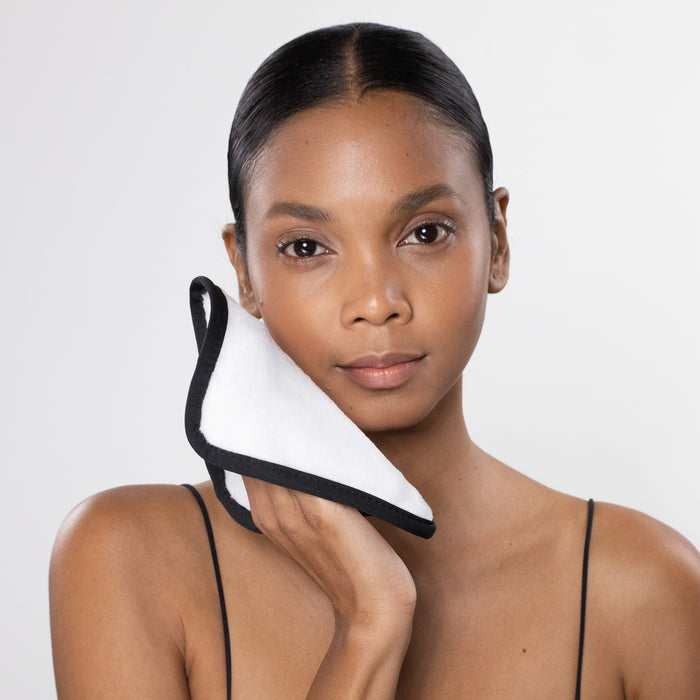 Woman holding a black and white product against her neck on a plain background
