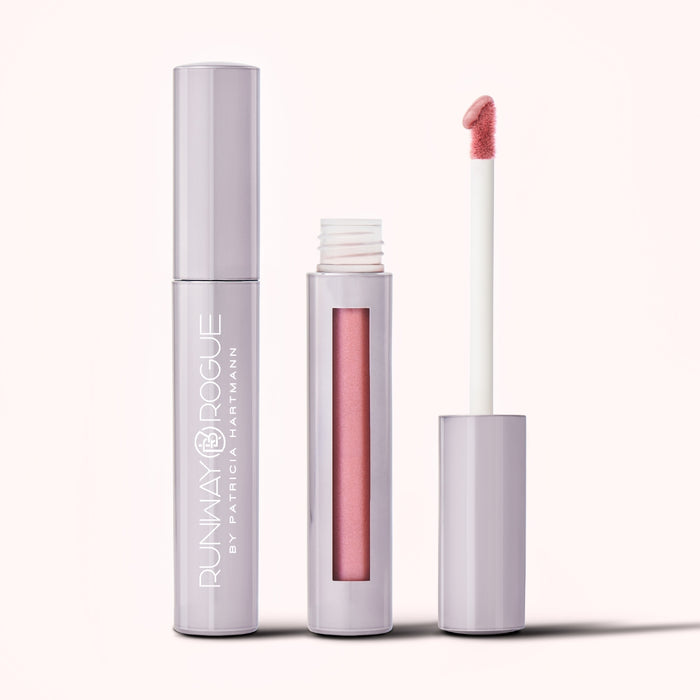 Two tubes of Runway Rogue's Silk Glam liquid lipstick in shade 'Trophy Wife'.  One tube is closed and displaying the Runway Rogue logo.  One tube is open, with the window of the bottom component displaying the pastel pink color, and the top component displaying the doe-foot wand with a drop of the pastel pink liquid lipstick.