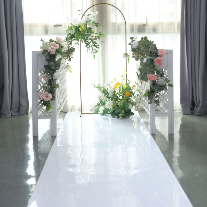 Wedding arch with floral decorations and a white aisle in a bright indoor setting.