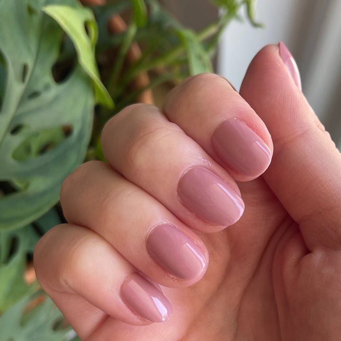 World Lit - Press-On | Extra Short | Round showing close-up of hand with glossy mauve extra short round press-on manicure