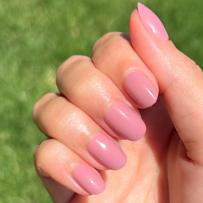 World Lit - Press-On | Extra Short | Round showing hand with mauve extra short round press-on manicure in natural light outdoors